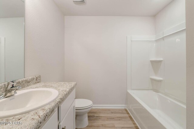 full bathroom featuring hardwood / wood-style flooring, vanity, shower / tub combination, and toilet