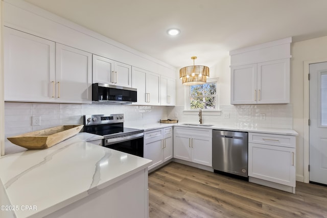 kitchen with pendant lighting, sink, stainless steel appliances, light stone countertops, and white cabinets