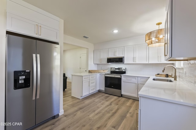 kitchen with sink, appliances with stainless steel finishes, white cabinetry, decorative backsplash, and decorative light fixtures