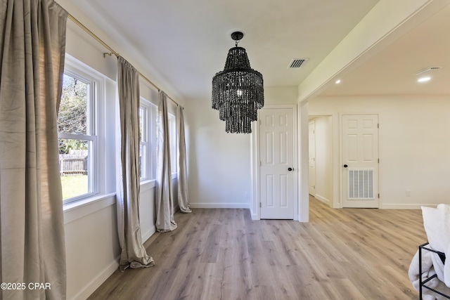 dining room with an inviting chandelier, plenty of natural light, and light hardwood / wood-style floors