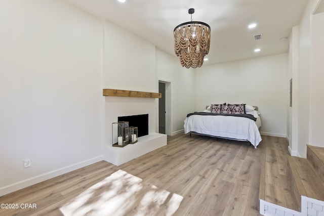 bedroom with a chandelier and light wood-type flooring