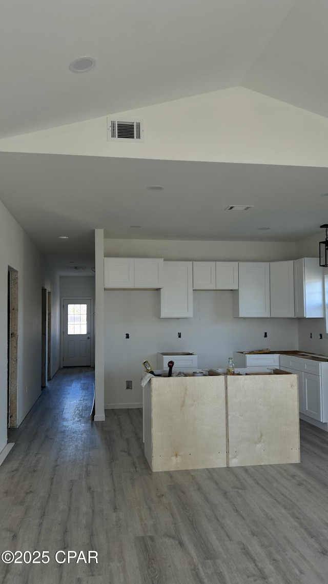 kitchen with a kitchen island, white cabinetry, lofted ceiling, and light hardwood / wood-style flooring