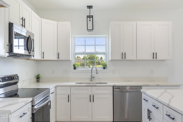 kitchen featuring white cabinets, a sink, pendant lighting, light stone countertops, and appliances with stainless steel finishes