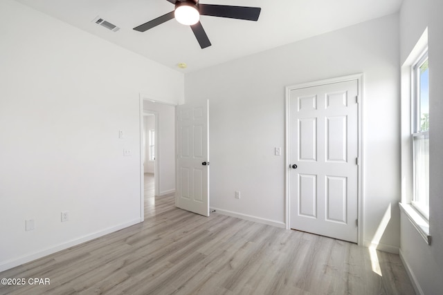 unfurnished bedroom with baseboards, a ceiling fan, visible vents, and light wood-style floors