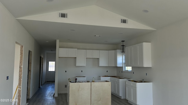 kitchen featuring lofted ceiling, a kitchen island, and white cabinets