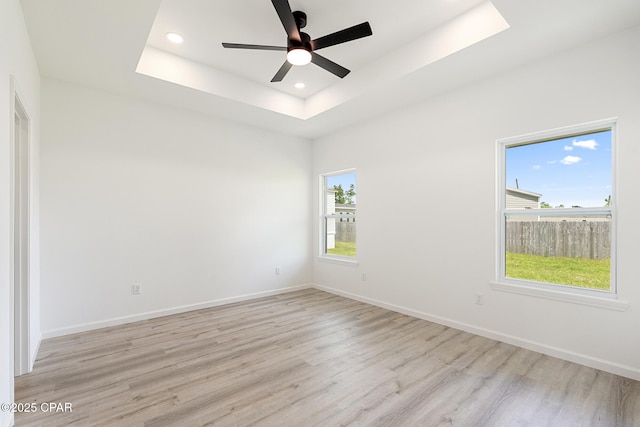 unfurnished room featuring a tray ceiling, baseboards, recessed lighting, a ceiling fan, and wood finished floors