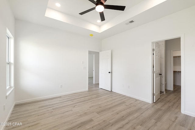 unfurnished bedroom featuring a walk in closet, light wood-style flooring, baseboards, visible vents, and recessed lighting