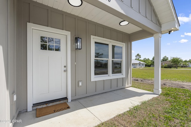 doorway to property featuring board and batten siding, a lawn, and a porch