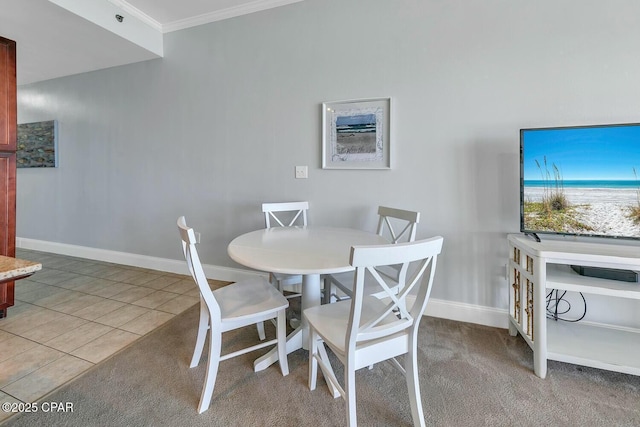 dining room featuring light carpet, light tile patterned floors, baseboards, and ornamental molding