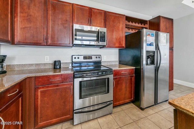 kitchen with light stone countertops, stainless steel appliances, and reddish brown cabinets