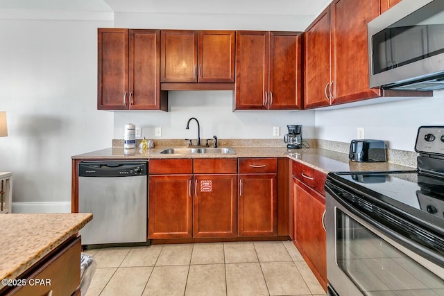 kitchen with dark brown cabinets, light countertops, light tile patterned floors, stainless steel appliances, and a sink