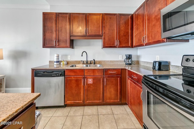 kitchen with a sink, light tile patterned floors, light countertops, reddish brown cabinets, and appliances with stainless steel finishes