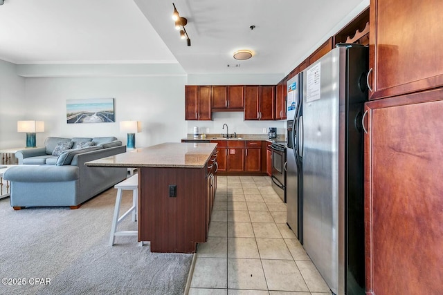 kitchen with a breakfast bar, stainless steel fridge with ice dispenser, a sink, a center island, and open floor plan