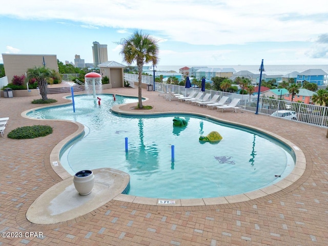 community pool with a patio area and fence