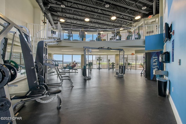 exercise room with baseboards and a towering ceiling