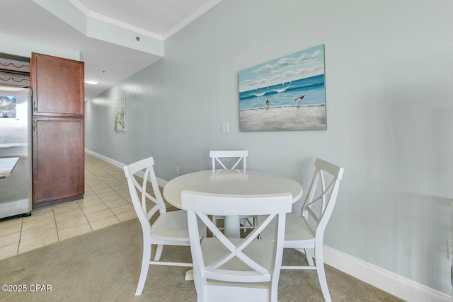 dining area featuring light tile patterned floors, baseboards, light colored carpet, and crown molding