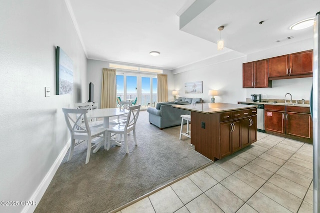 kitchen featuring a center island, baseboards, open floor plan, light colored carpet, and light tile patterned floors