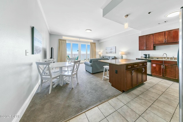 kitchen featuring light tile patterned floors, visible vents, light countertops, a kitchen island, and open floor plan