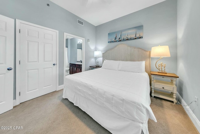 carpeted bedroom featuring visible vents, baseboards, and ensuite bathroom