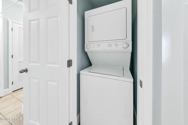 clothes washing area with light tile patterned floors and stacked washer and dryer