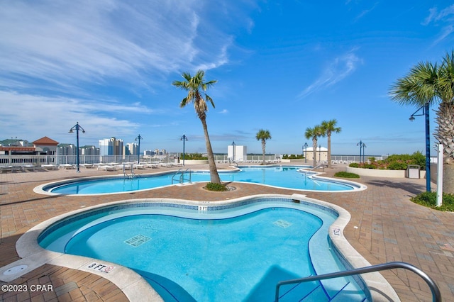 community pool with fence and a patio