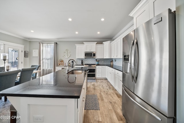 kitchen featuring sink, white cabinetry, crown molding, a large island with sink, and stainless steel appliances