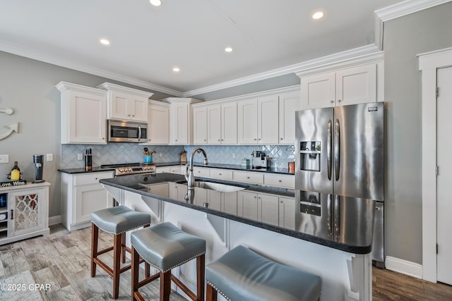 kitchen with a kitchen island with sink, sink, white cabinets, and appliances with stainless steel finishes