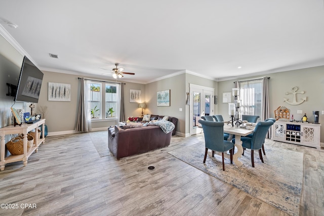 dining space with crown molding, a wealth of natural light, and light wood-type flooring