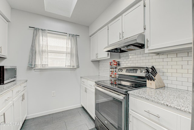 kitchen featuring stainless steel appliances, white cabinetry, tasteful backsplash, and light stone counters