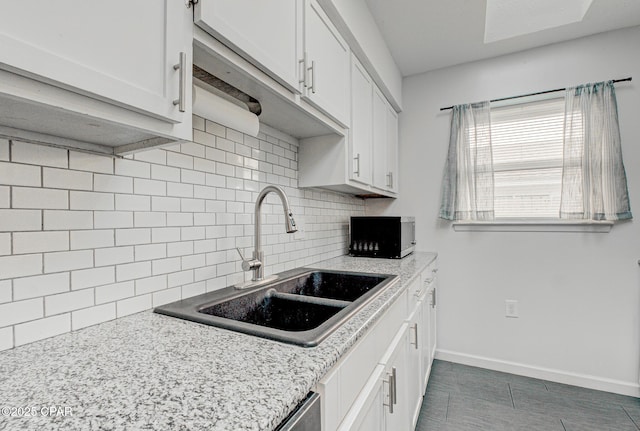 kitchen with tasteful backsplash, sink, light stone counters, and white cabinets