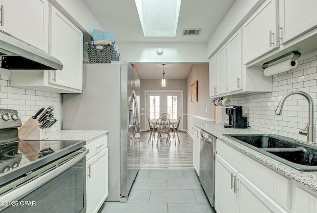 kitchen featuring stainless steel appliances, extractor fan, sink, and white cabinetry