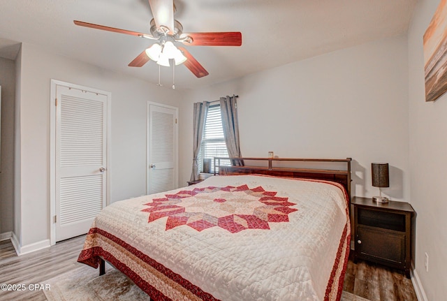 bedroom featuring wood-type flooring, two closets, and ceiling fan