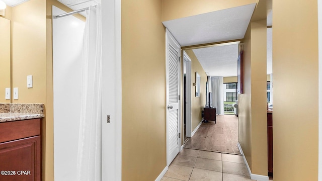 hallway with light tile patterned floors and baseboards