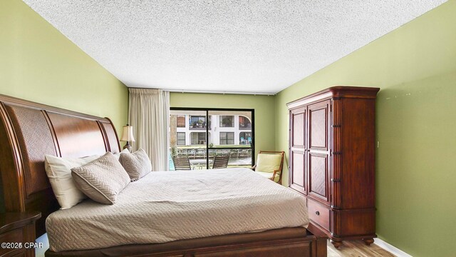 bedroom featuring baseboards, light wood finished floors, and a textured ceiling