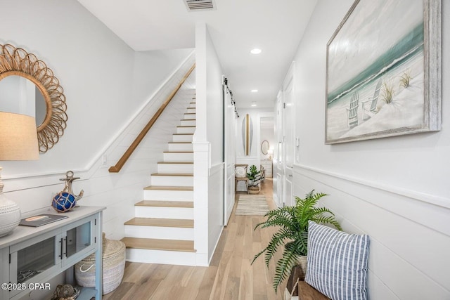 stairway featuring wood-type flooring and a barn door