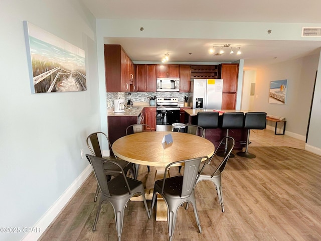 dining area featuring visible vents, baseboards, and light wood-style flooring