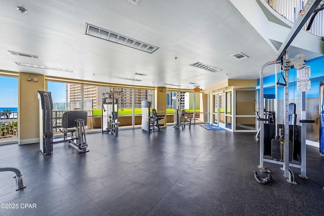 exercise room featuring visible vents, a textured ceiling, and expansive windows