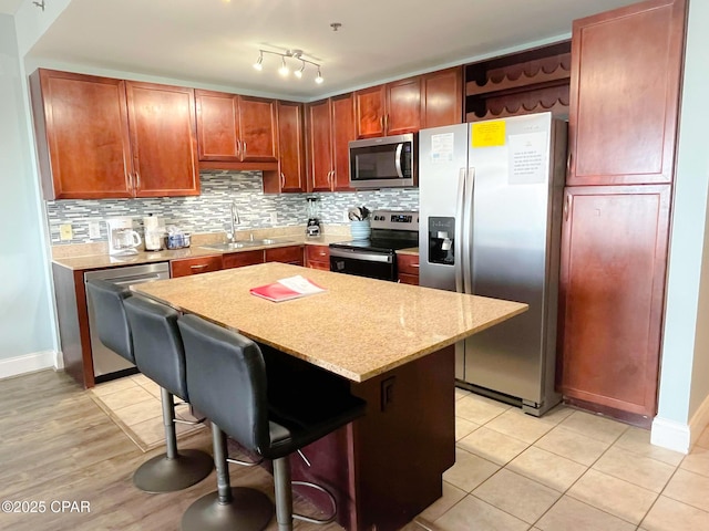 kitchen featuring a breakfast bar, a sink, open shelves, appliances with stainless steel finishes, and decorative backsplash