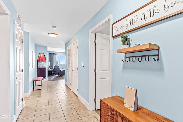 corridor featuring light tile patterned floors and baseboards