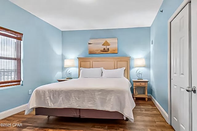 bedroom with wood finished floors, baseboards, and a closet