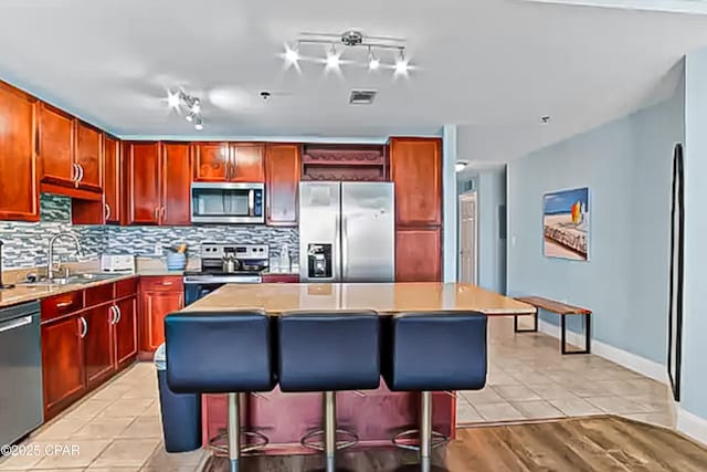 kitchen with decorative backsplash, a center island, visible vents, and stainless steel appliances