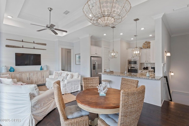 dining space featuring a raised ceiling, crown molding, dark hardwood / wood-style floors, and ceiling fan with notable chandelier