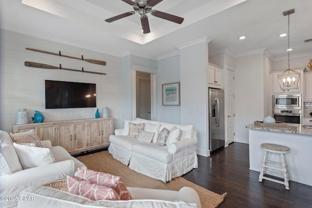 living room featuring dark hardwood / wood-style flooring, crown molding, ceiling fan with notable chandelier, and a raised ceiling