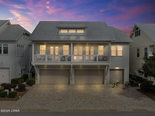 view of front of home with central AC unit, a garage, and a balcony