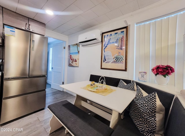 dining space featuring light wood-style floors, crown molding, and a wall mounted air conditioner