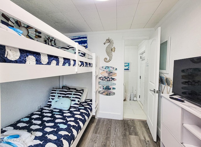 bedroom with crown molding and wood finished floors