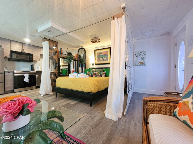 bedroom featuring freestanding refrigerator, baseboards, and wood finished floors