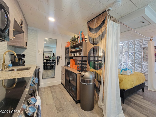 kitchen with light wood-style floors, black microwave, a sink, and light stone counters