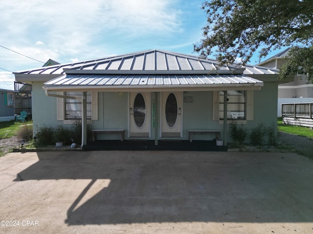 view of front of house with metal roof, a porch, a standing seam roof, and stucco siding