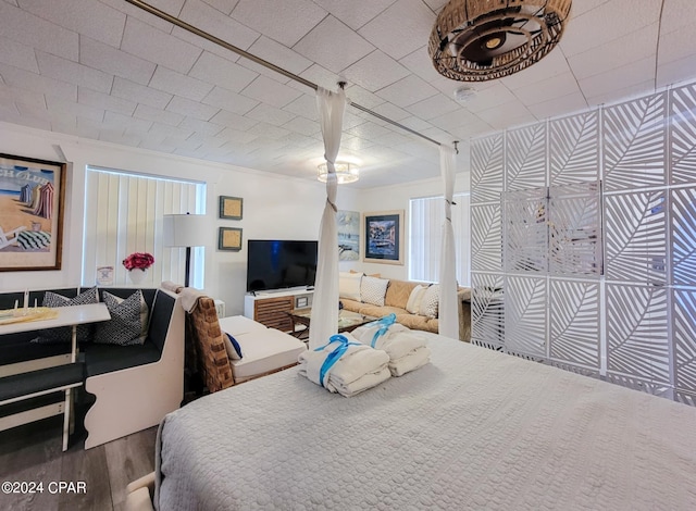 bedroom with ornamental molding and wood finished floors